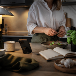 Person preparing food while a protected phone stands on a kitchen counter